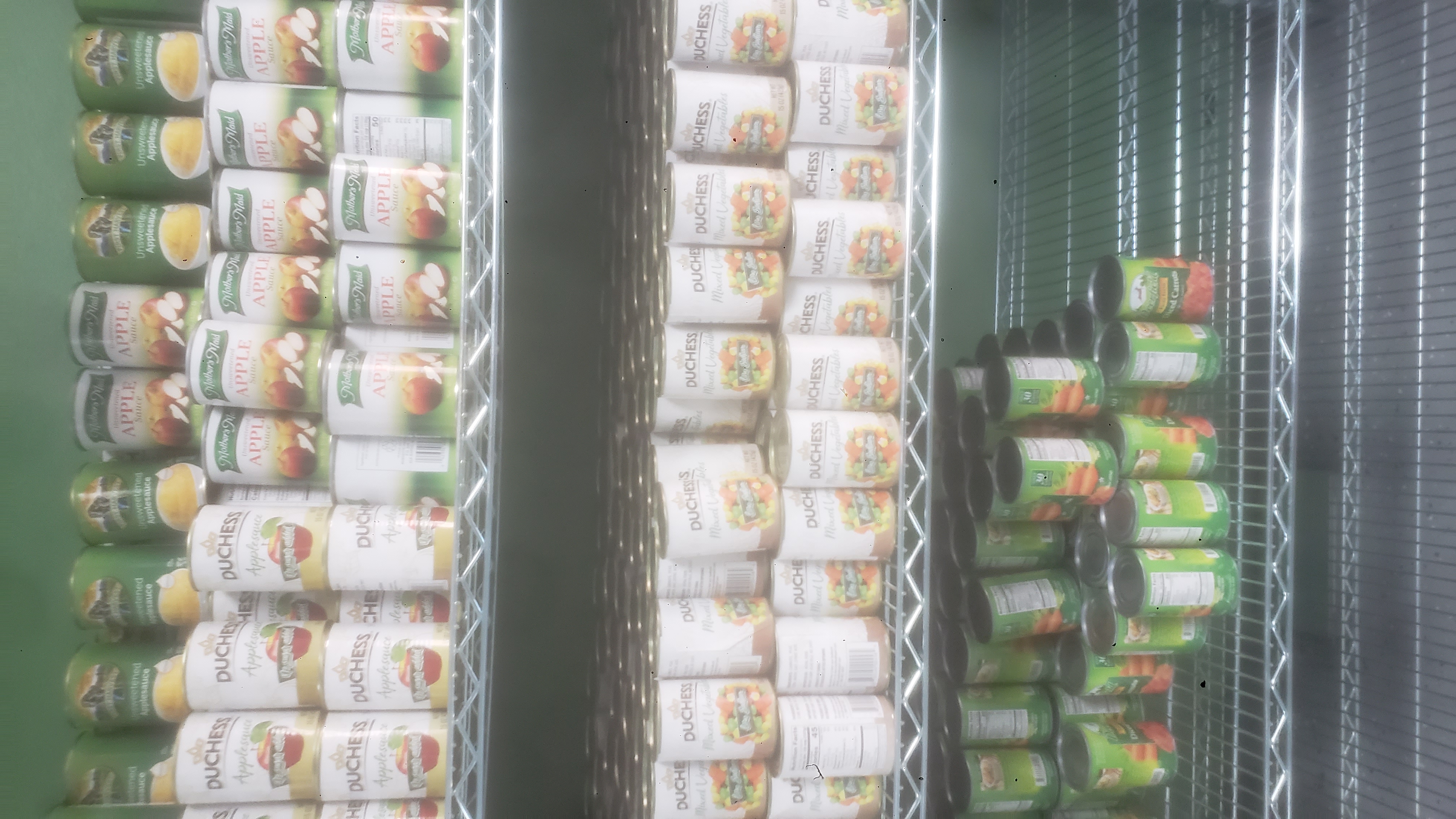Shelves full of canned apple sauce and canned sliced carrots.